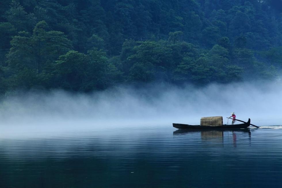 云雾萦绕山间,一叶小舟飘在江面,静如止水,又震撼心灵.